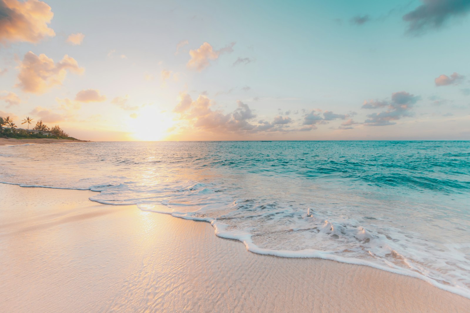 Sunrise over a NSW beach with coastal apartment buildings on the headland