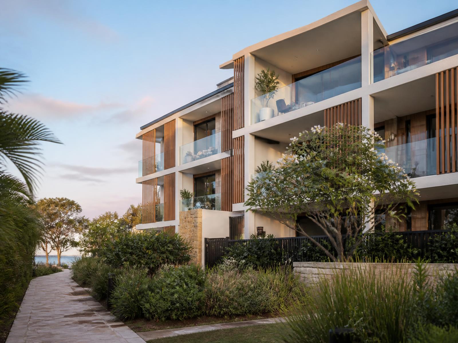 Modern low-rise Australian coastal apartment building with lush landscaping at sunrise